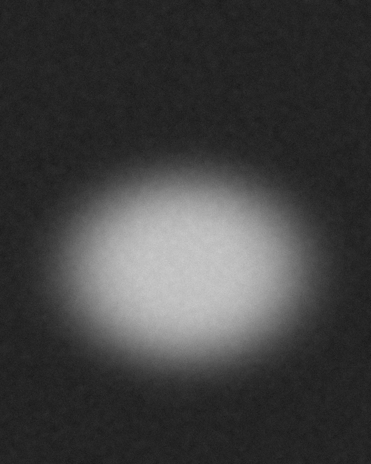 An empty studio after a sitting: grey backdrop paper, one light still on, nobody in the room.